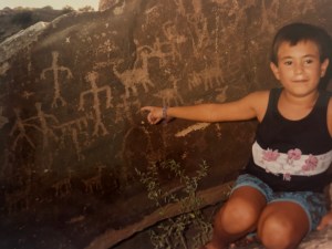 Young boy pointing to a rock with petroglyphs.